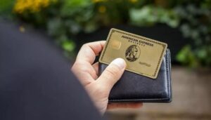 The American Express® Gold Card being held up in front of a bright blue wall